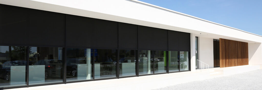Modern building with glass windows, black roller blinds, and wooden slat section.
