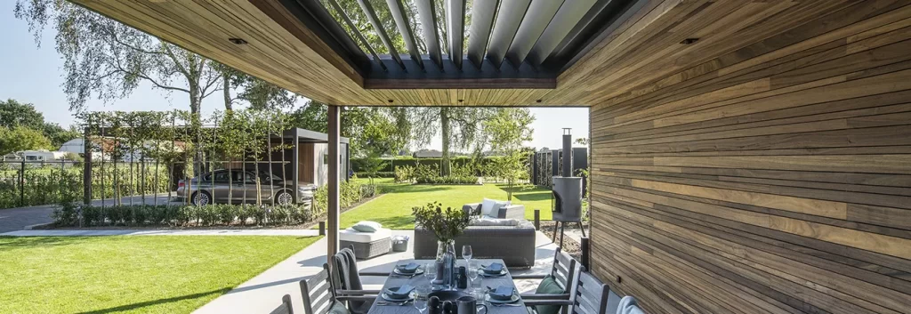 Outdoor patio with wooden pergola, dining table, and chairs set for a meal.