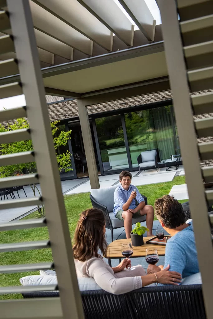 Boy smiling and talking to two adults outdoors.