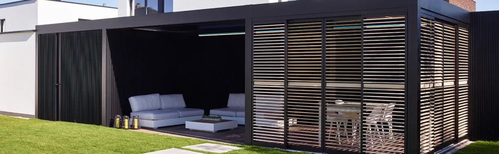 Outdoor patio with pergola, cushioned sofas, small table.