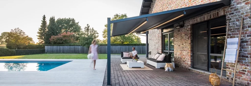 Modern brick house with patio, man seated, woman near pool.